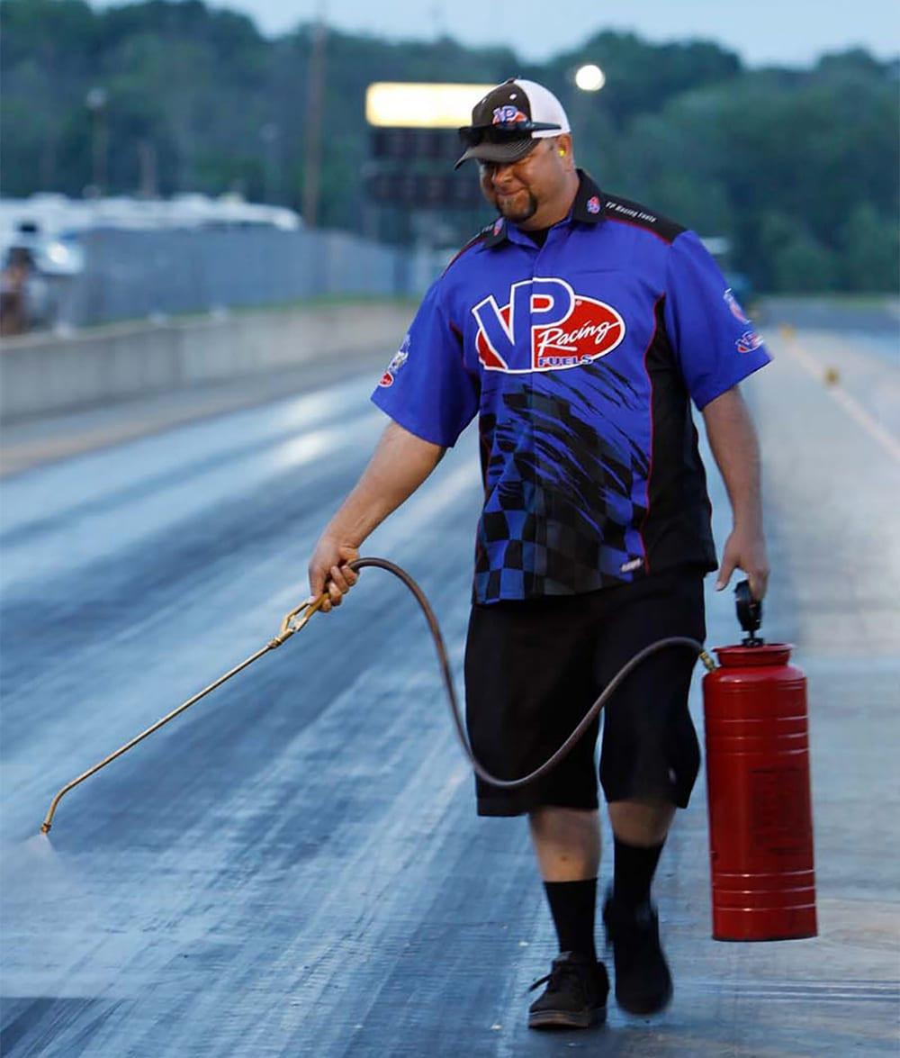 image of a race track employee spraying VP Lane Choice 7 traction compound on a track